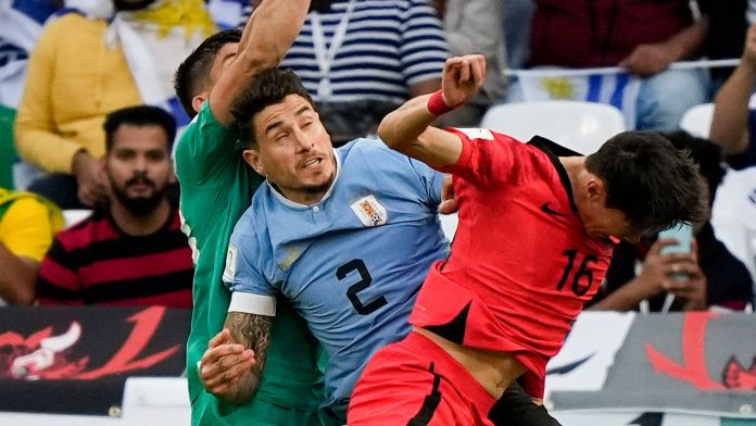 Uruguay's goalkeeper Sergio Rochet punches clear under pressure from Ui-Jo Hwang